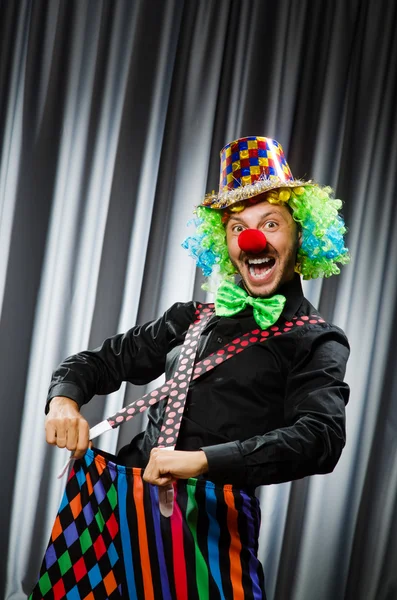 Payaso divertido en concepto humorístico contra cortina —  Fotos de Stock