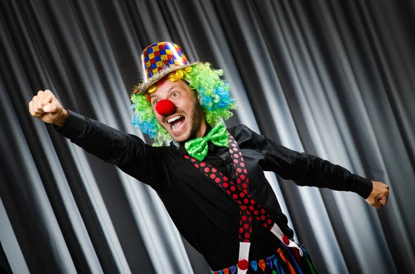 Clown divertente nel concetto umoristico contro tenda — Foto Stock