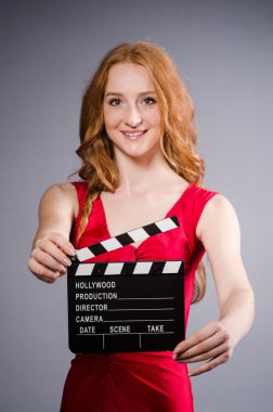 Film tahtası olan kırmızı elbiseli bir kadın.