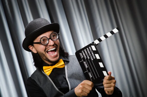 Hombre divertido con el tablero de la película contra la cortina —  Fotos de Stock