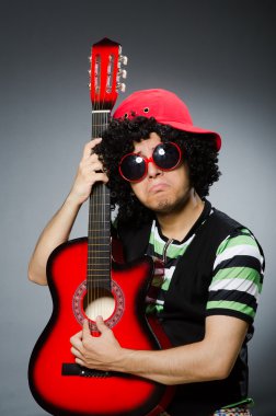 Komik saç kesimi ve gitarı olan adam.