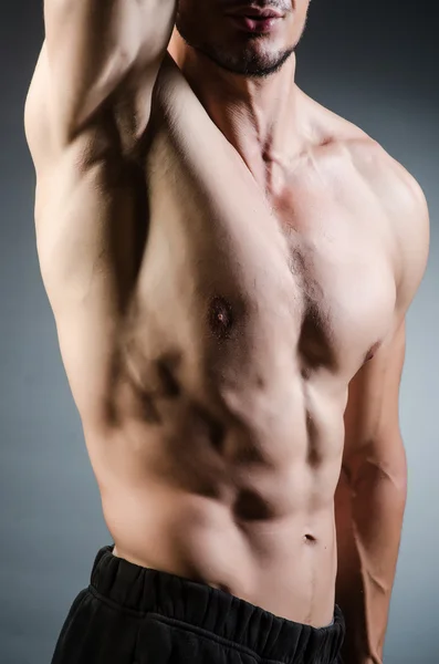 Muscular man posing in dark studio — Stock Photo, Image