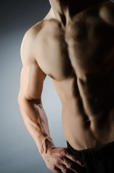 Muscular man posing in dark studio — Stock Photo, Image