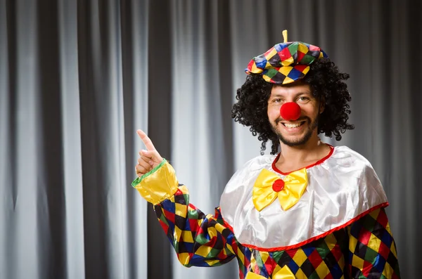 Lustiger Clown mit humorvollem Konzept gegen Vorhang — Stockfoto