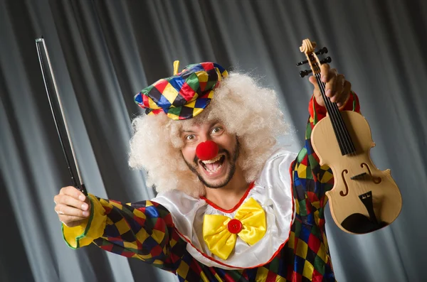 Grappige clown plyaing viool tegen gordijn — Stockfoto