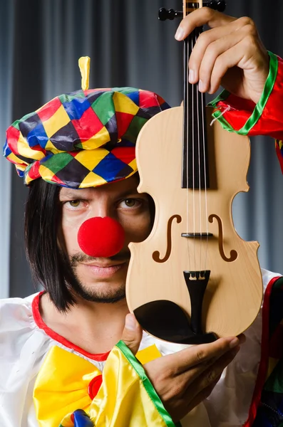 Vtipné klaun překrytí housle proti oponě — Stock fotografie