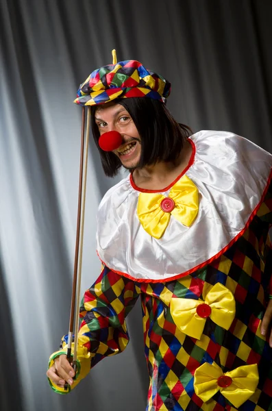 Lustiger Clown spielt Geige gegen Vorhang — Stockfoto