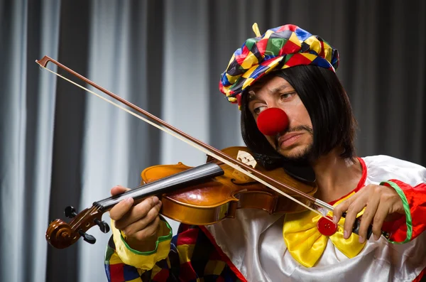 Engraçado palhaço plyaing violino contra cortina — Fotografia de Stock