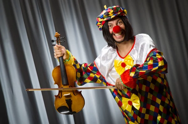 Смешной клоун прилипает скрипку к занавеске — стоковое фото