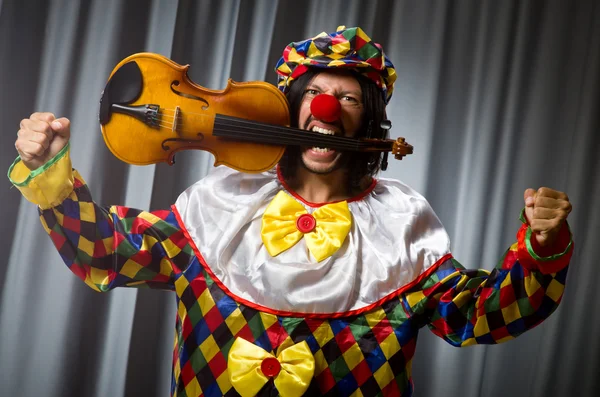 Engraçado palhaço plyaing violino contra cortina — Fotografia de Stock