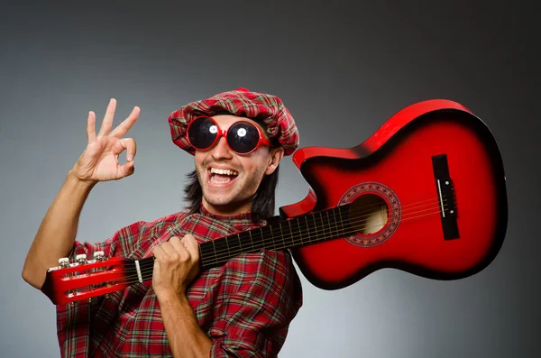 面白いスコッツマン赤いギターを弾く — ストック写真