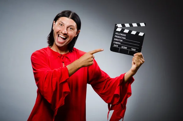 Homme en robe rouge avec film clapboard — Photo