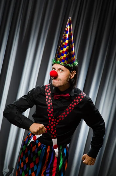 Lustiger Clown mit humorvollem Konzept gegen Vorhang — Stockfoto