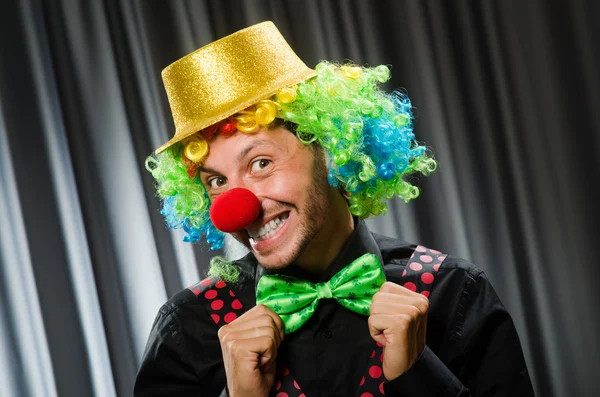 Lustiger Clown mit humorvollem Konzept gegen Vorhang — Stockfoto