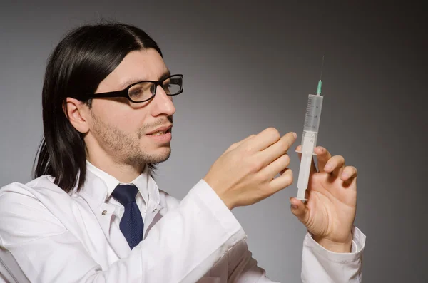 Mladý lékař muž s injekční stříkačkou na šedém pozadí — Stock fotografie