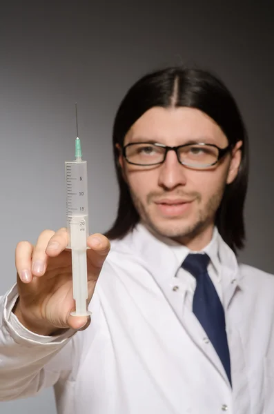 Mladý lékař muž s injekční stříkačkou na šedém pozadí — Stock fotografie