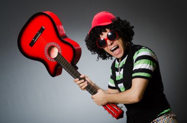 Komik saç kesimi ve gitarı olan adam.