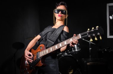 Konser sırasında gitar çalan genç bir kadın.