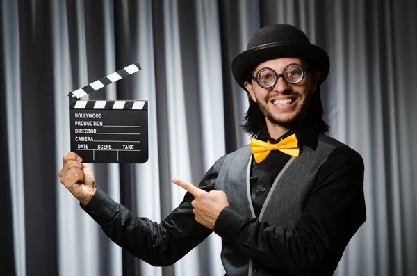 Vtipný muž s filmovou deskou proti závěsu — Stock fotografie