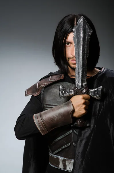 Boze ridder met zwaard tegen donkere achtergrond — Stockfoto