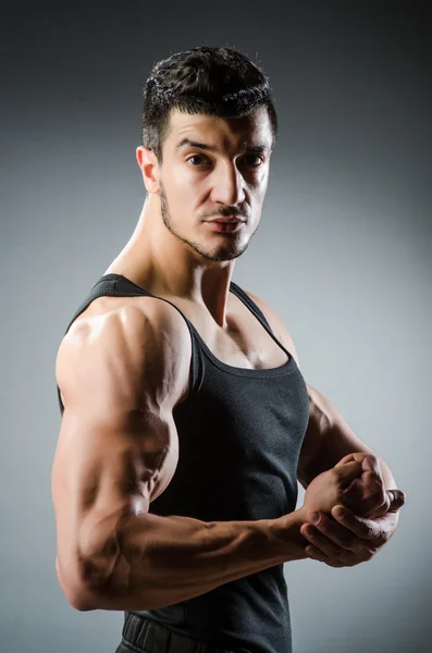 Muscular man posing in dark studio — Stock Photo, Image