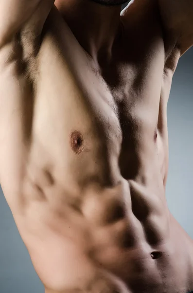 어두운 스튜디오에서 포즈를 취하는 근육질의 남자 — 스톡 사진