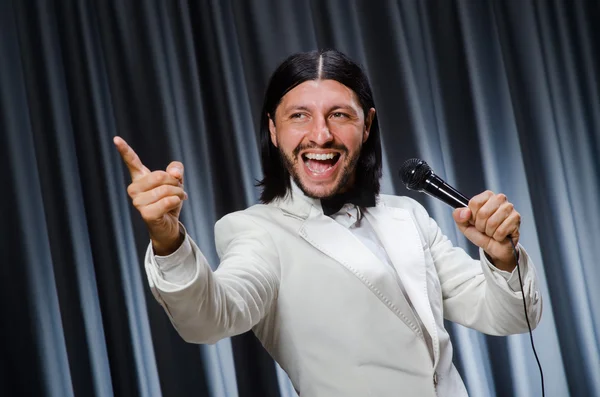 Man zingt voor gordijn in karaoke concept — Stockfoto