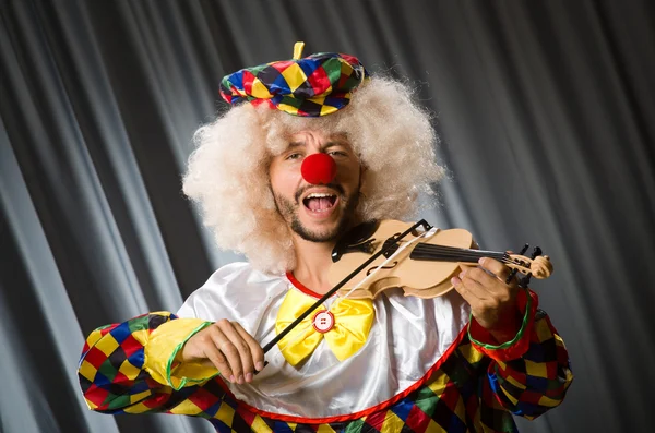 Funny clown plyaing violin against curtain — Stock Photo, Image