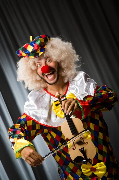 Lustiger Clown spielt Geige gegen Vorhang — Stockfoto