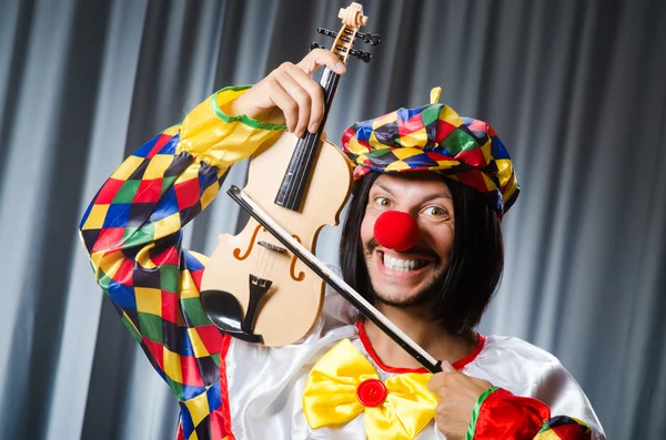 Engraçado palhaço plyaing violino contra cortina — Fotografia de Stock