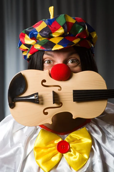 Funny clown plyaing violin against curtain — Stock Photo, Image