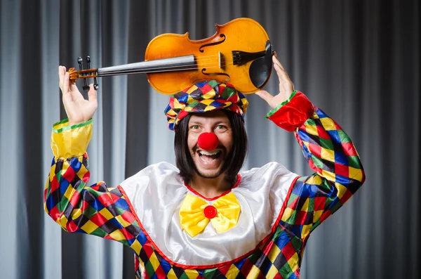 Lustiger Clown spielt Geige gegen Vorhang — Stockfoto