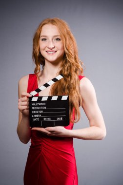 Film tahtası olan kırmızı elbiseli bir kadın.