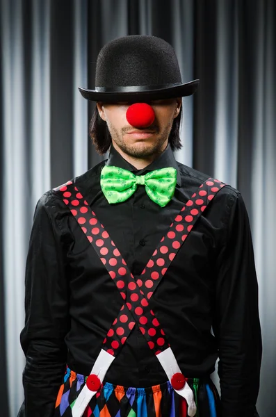 Lustiger Clown mit humorvollem Konzept gegen Vorhang — Stockfoto