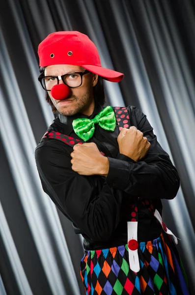 Lustiger Clown mit humorvollem Konzept gegen Vorhang — Stockfoto