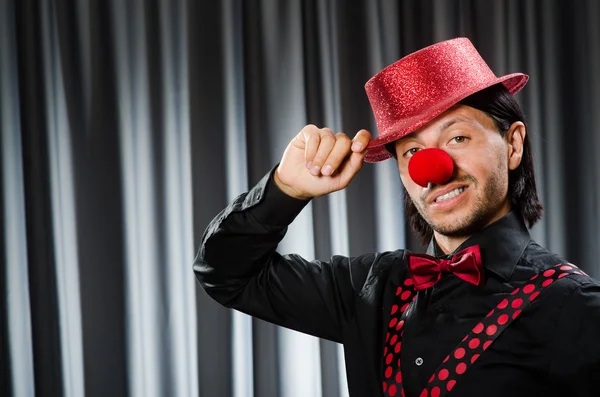 Lustiger Clown mit humorvollem Konzept gegen Vorhang — Stockfoto