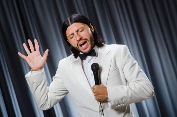 Человек поет перед занавесом в караоке концепции