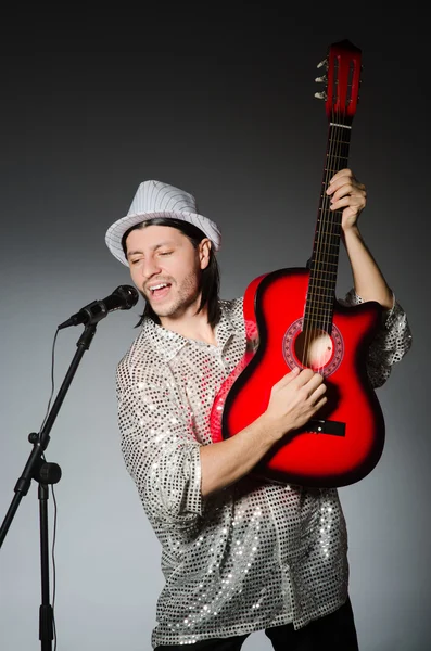Человек с гитарой поет с микрофоном — стоковое фото
