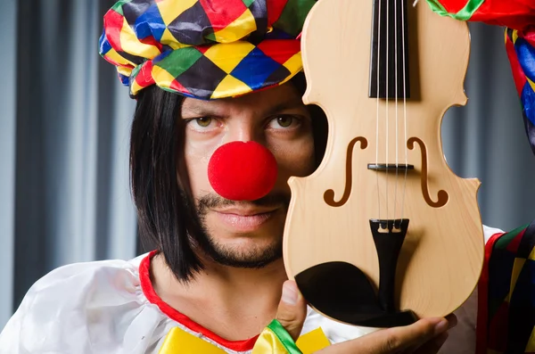 Funny clown plyaing violin against curtain — Stock Photo, Image