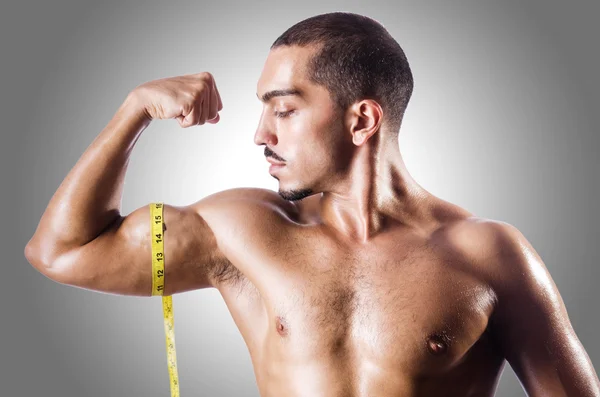 Homem muscular medindo seus músculos — Fotografia de Stock