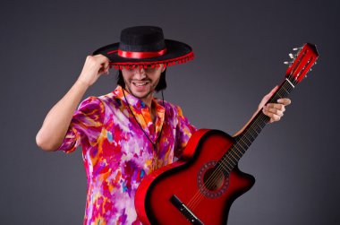 Gitarlı bir sombrero giyen adam.