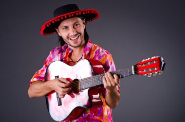 Gitarlı bir sombrero giyen adam.