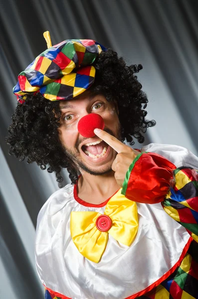 Lustiger Clown mit humorvollem Konzept gegen Vorhang — Stockfoto