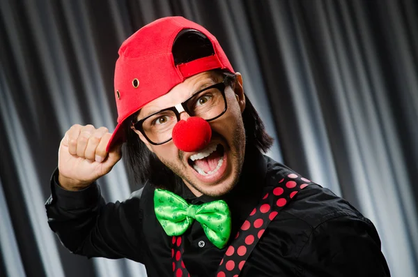 Clown divertente nel concetto umoristico contro tenda — Foto Stock