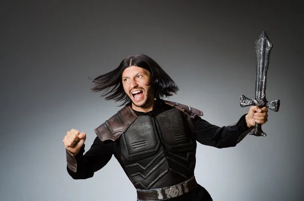 Angry knight with sword against dark background — Stock Photo, Image