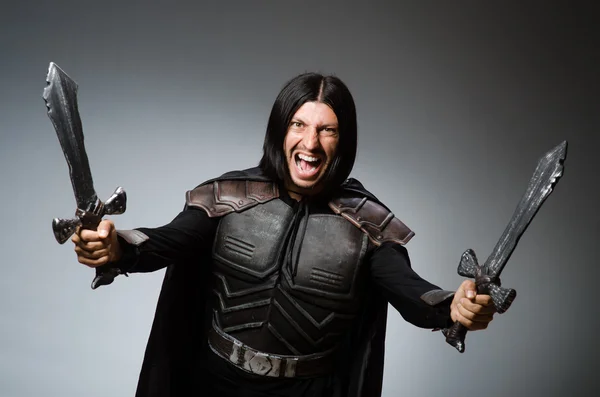 Angry knight with sword against dark background — Stock Photo, Image