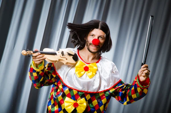 Lustiger Clown spielt Geige gegen Vorhang — Stockfoto