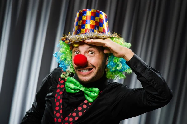 Payaso divertido en concepto humorístico contra cortina —  Fotos de Stock