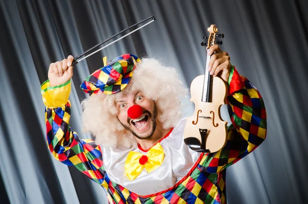 Vtipné klaun překrytí housle proti oponě — Stock fotografie