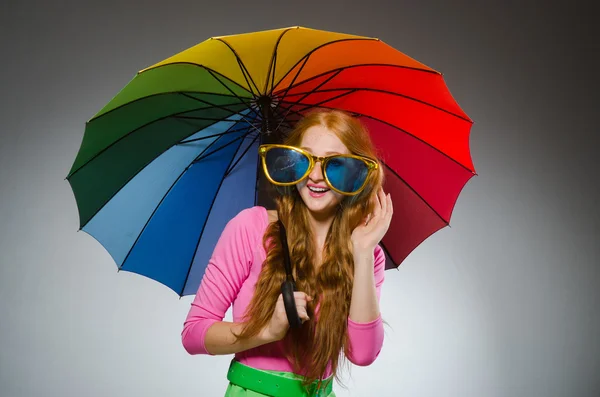 Woman holding colourful umbrella in studio — Stock Photo, Image